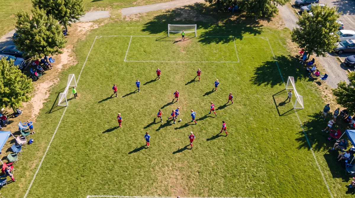 Overhead view of children playing soccer on a sunny field